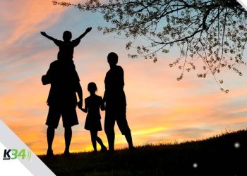 La silueta de una familia compartiendo feliz en un parque mientras se da el ocaso