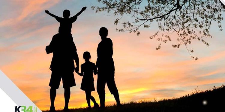 La silueta de una familia compartiendo feliz en un parque mientras se da el ocaso